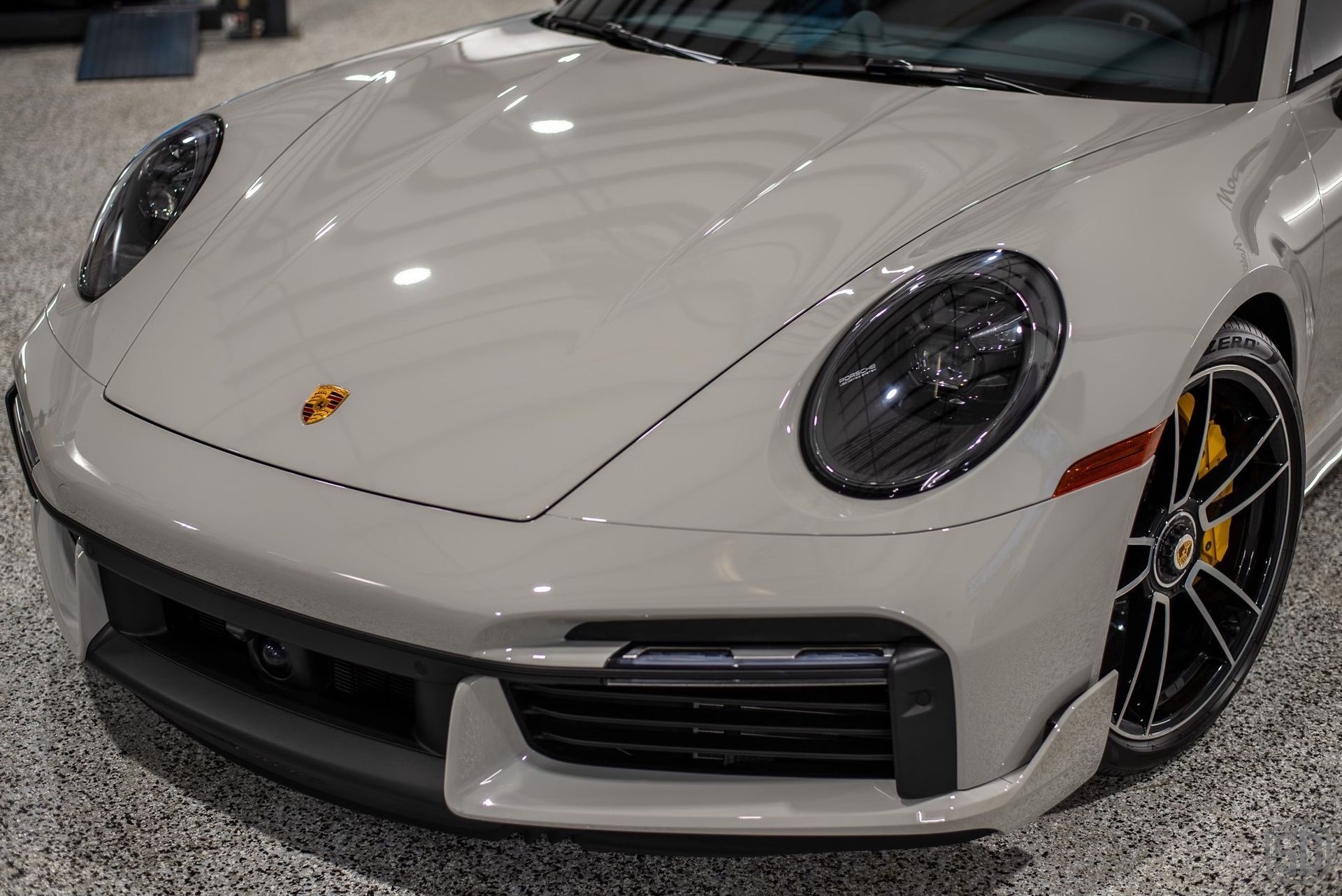 A white porsche 911 turbo s is parked in a garage.