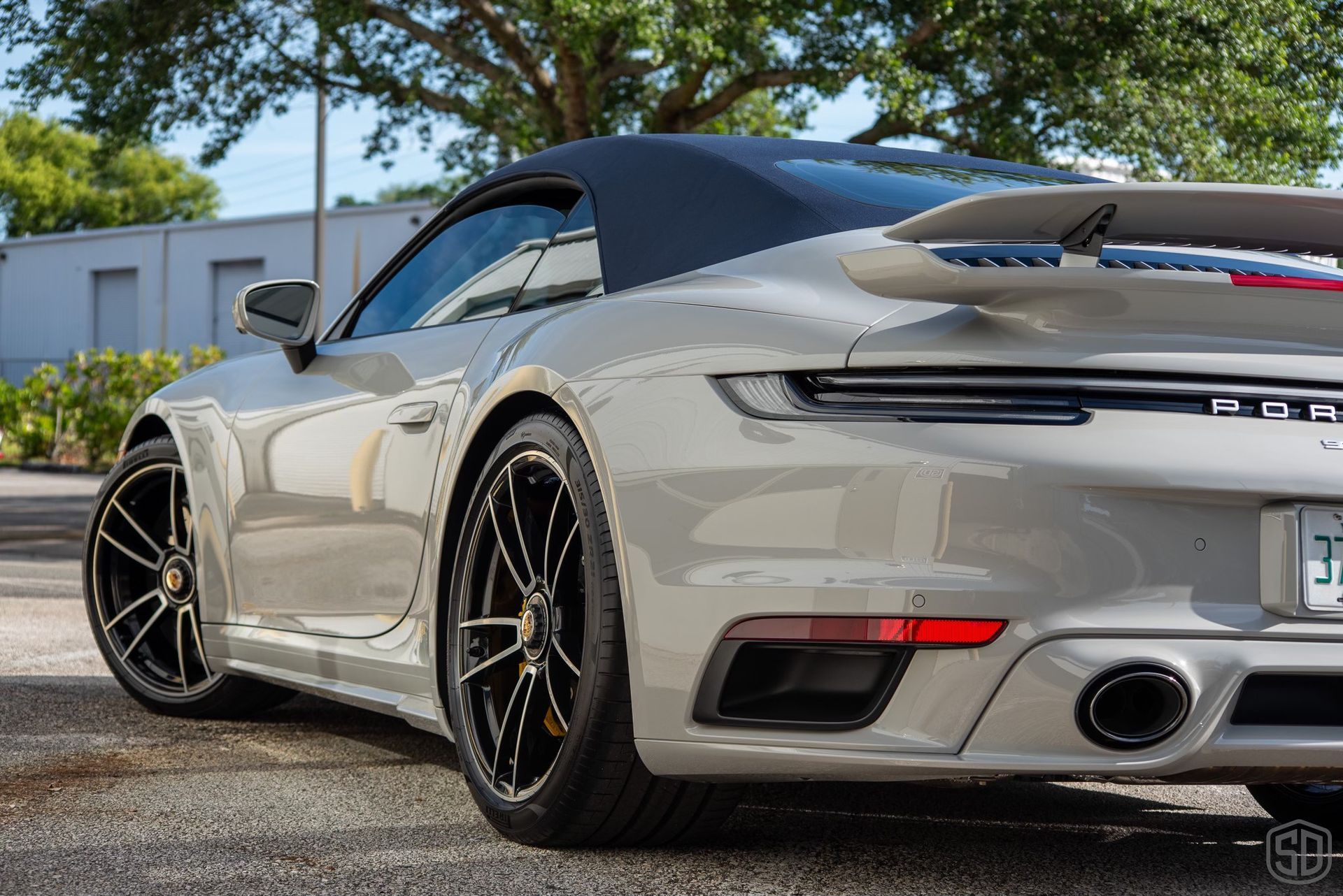 A silver porsche 911 turbo s convertible is parked in a parking lot.