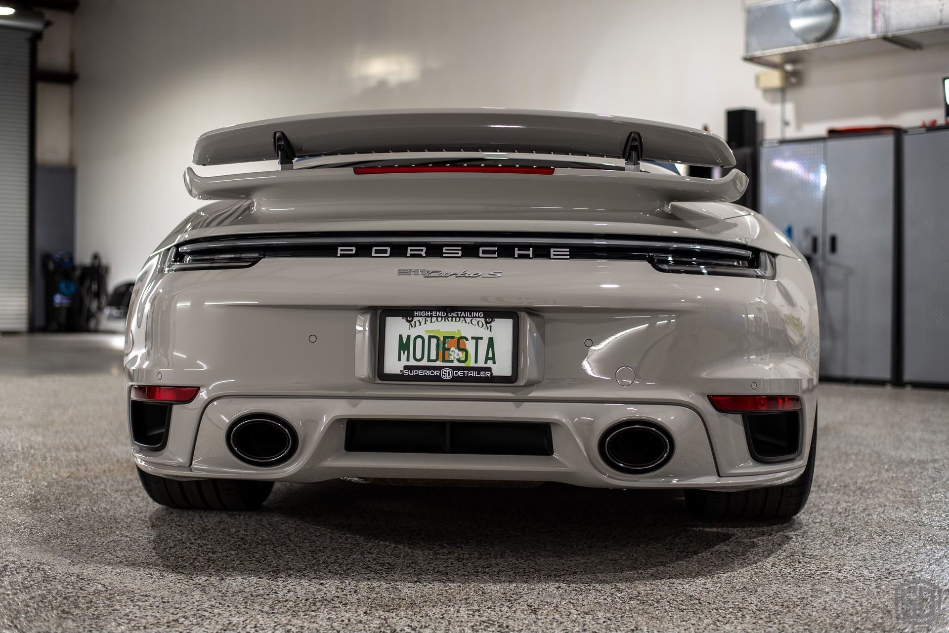 A white porsche turbo s convertible is parked in a garage.