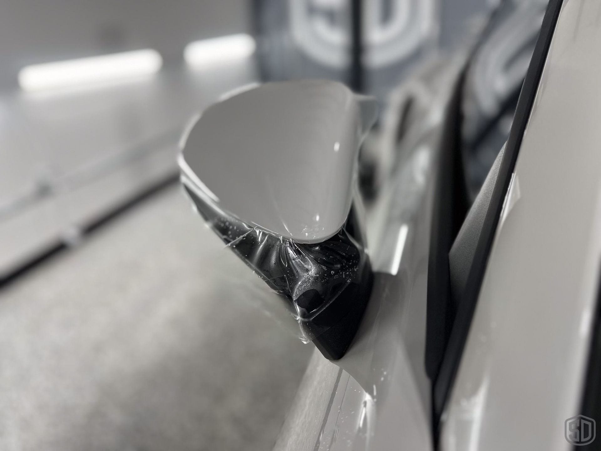 A close up of a car with a side mirror wrapped in plastic.