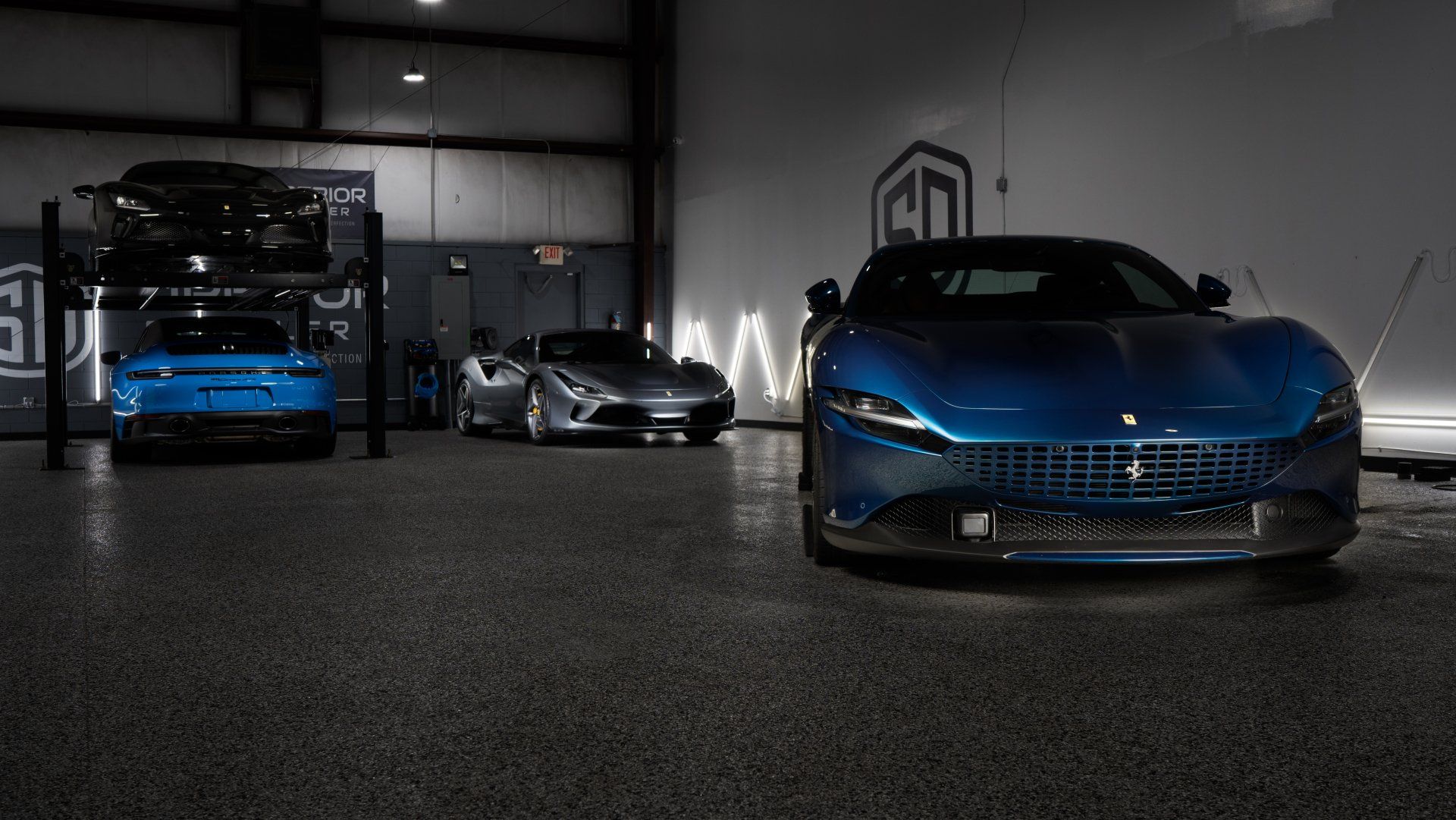 Three blue sports cars are parked in a garage.