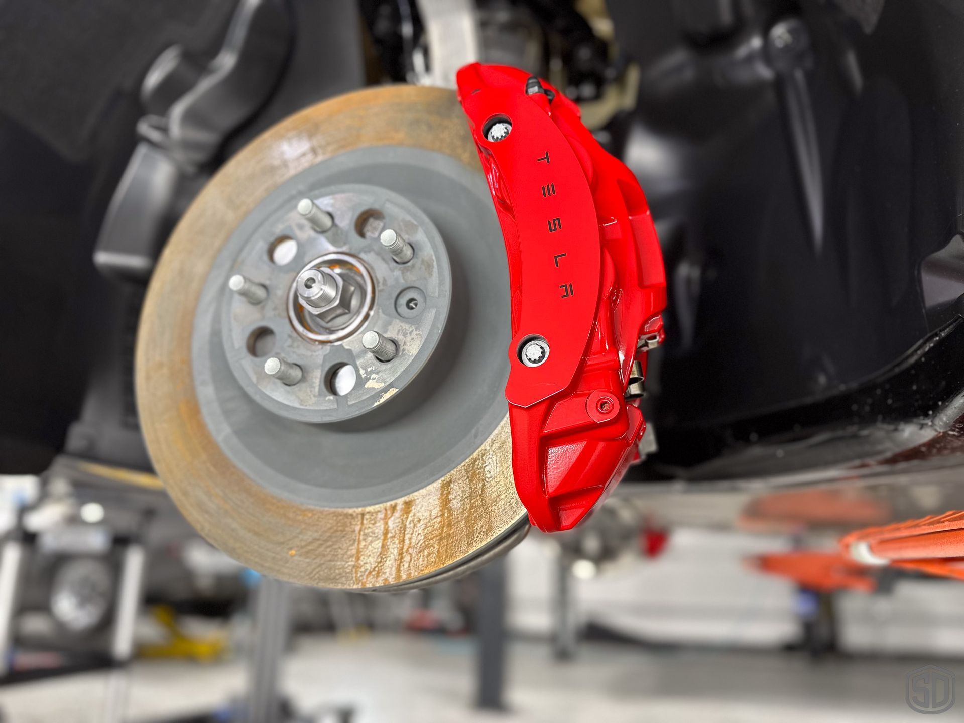 A close up of a red brake caliper on a car.