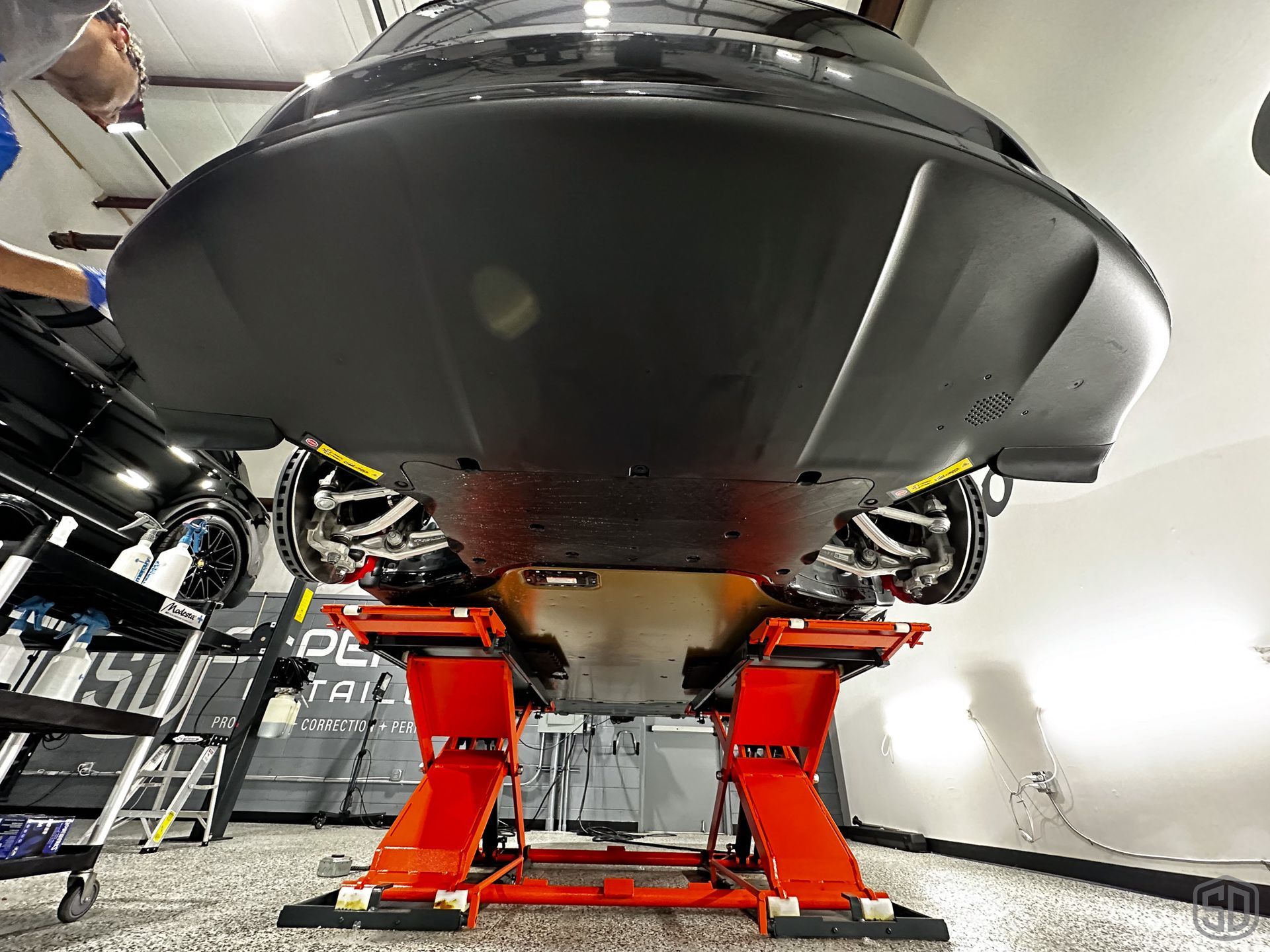 A car is sitting on a lift in a garage.