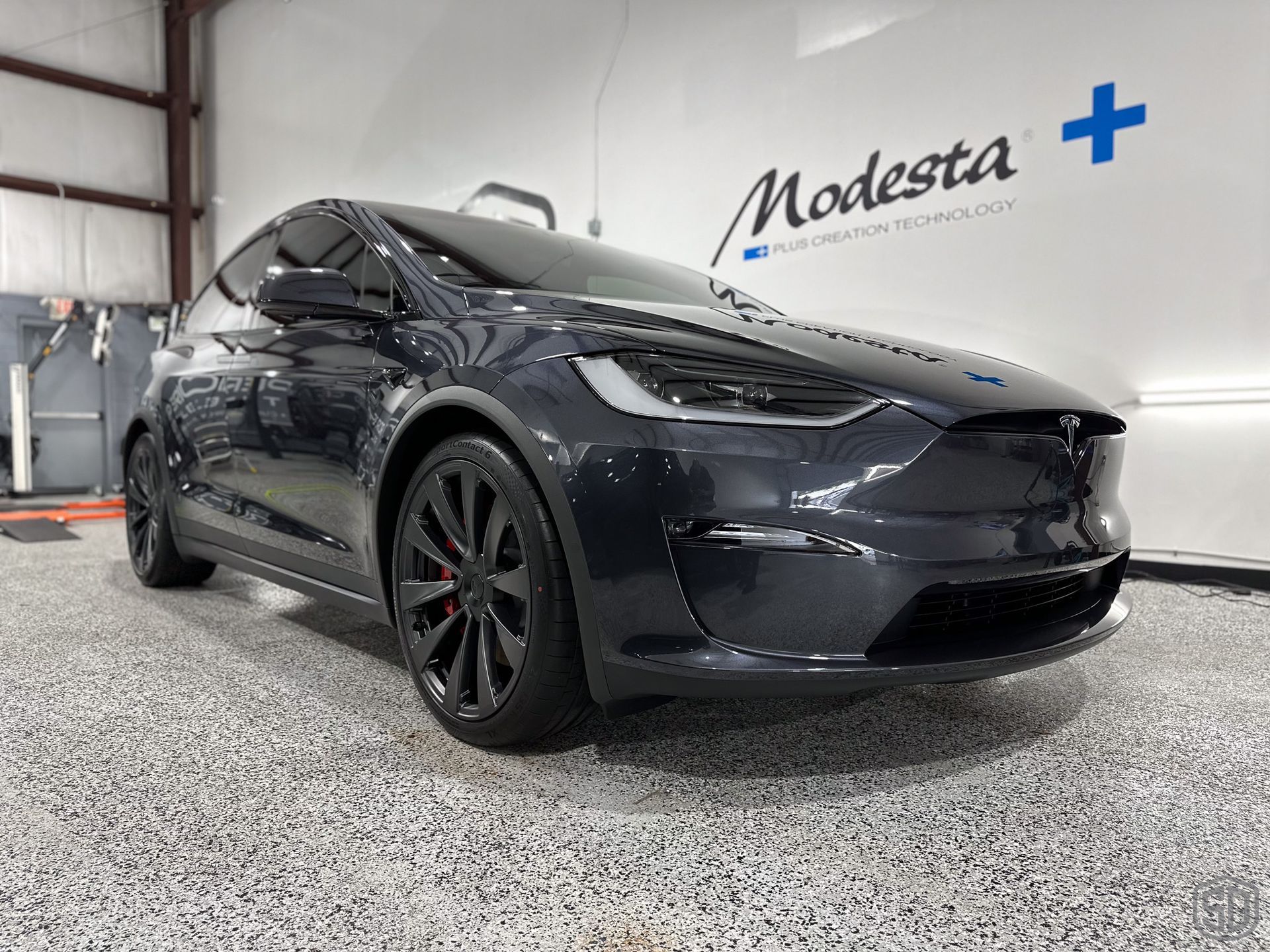 A black tesla model x is parked in a garage.