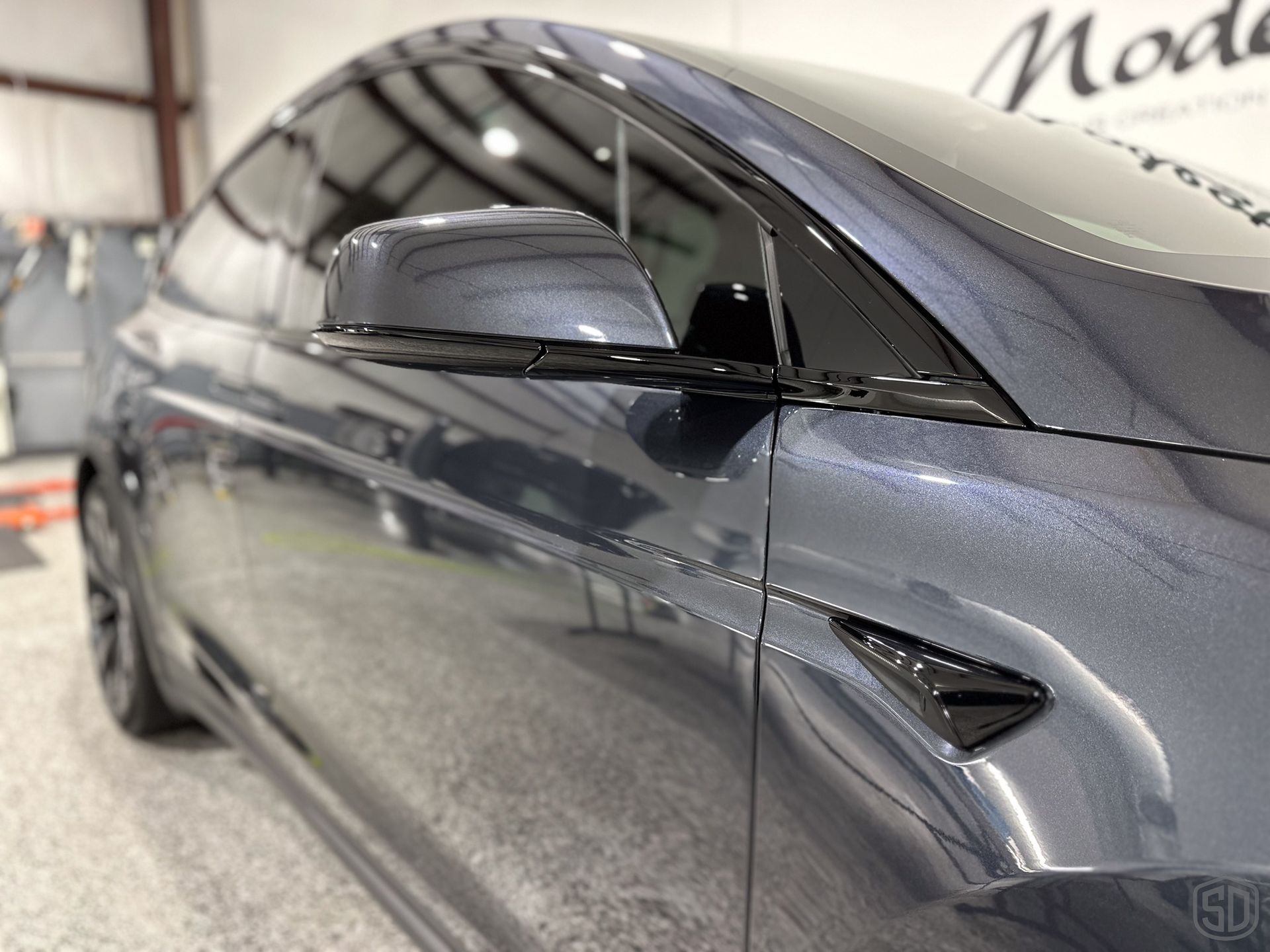 A gray tesla model x is parked in a garage