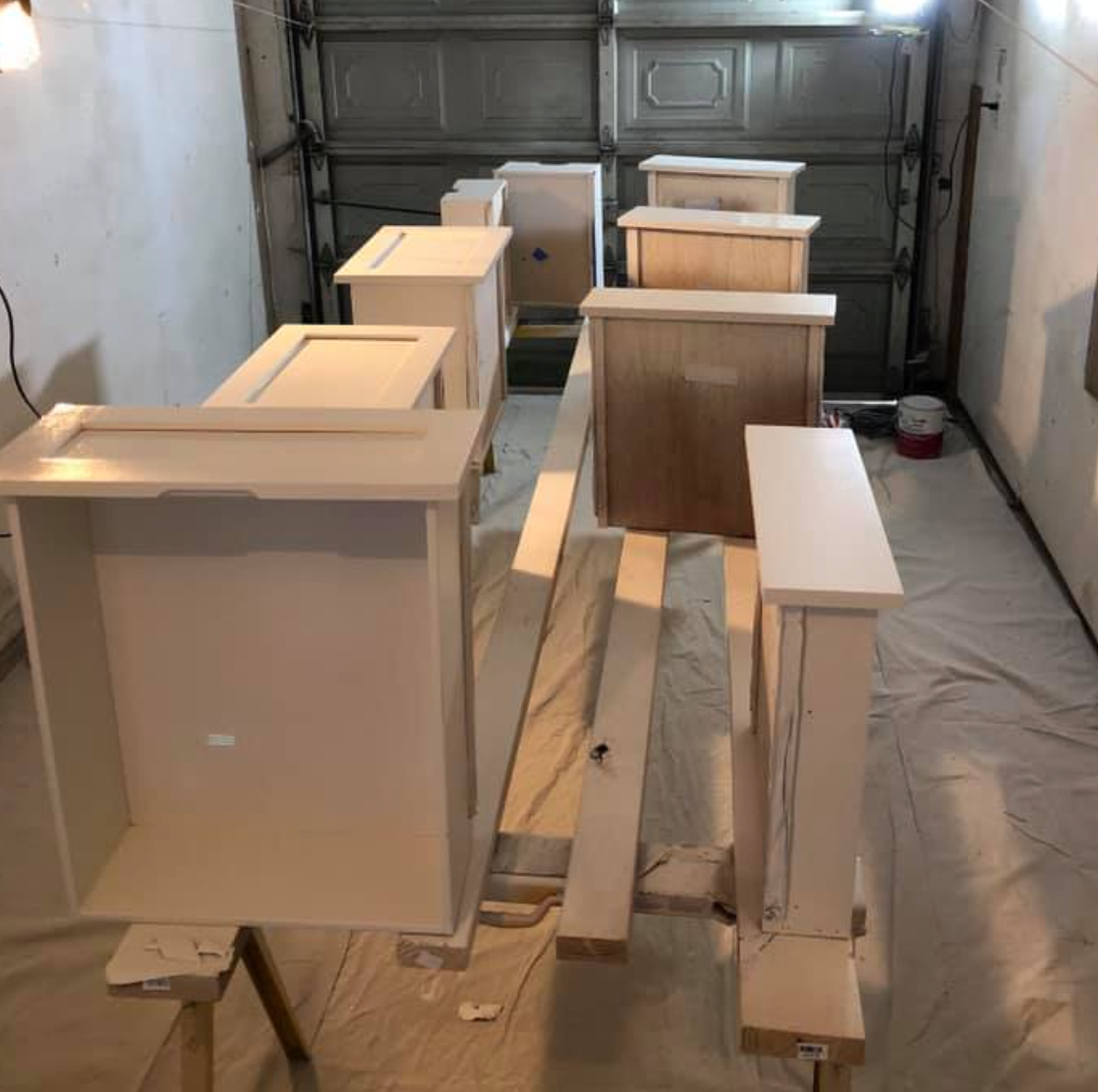 Cabinets in a garage being painted white on sawhorses.