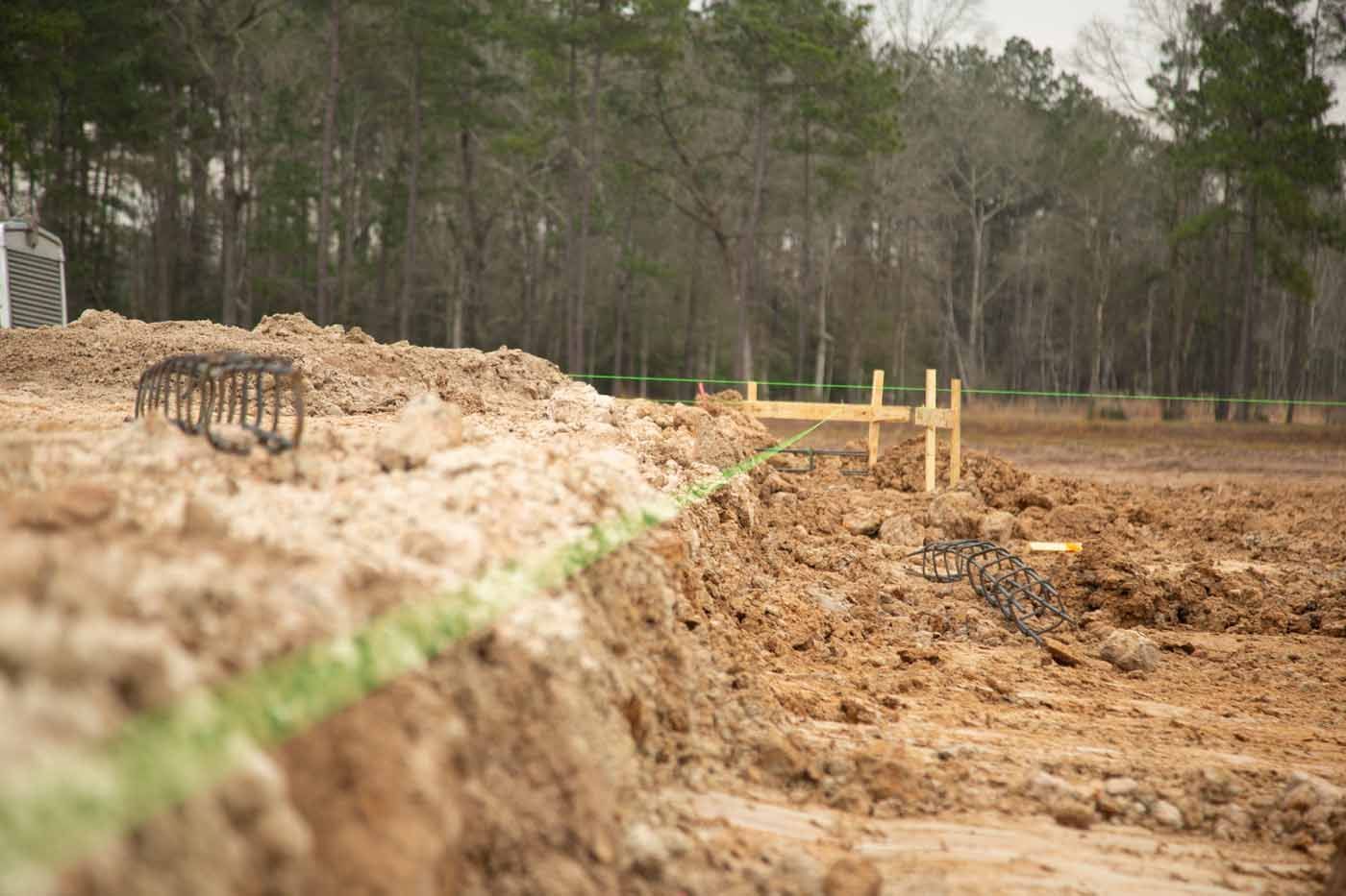 A construction site with a lot of dirt and trees in the background.