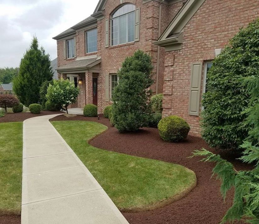 Brick house with landscaped yard, pathway, and mulch beds.
