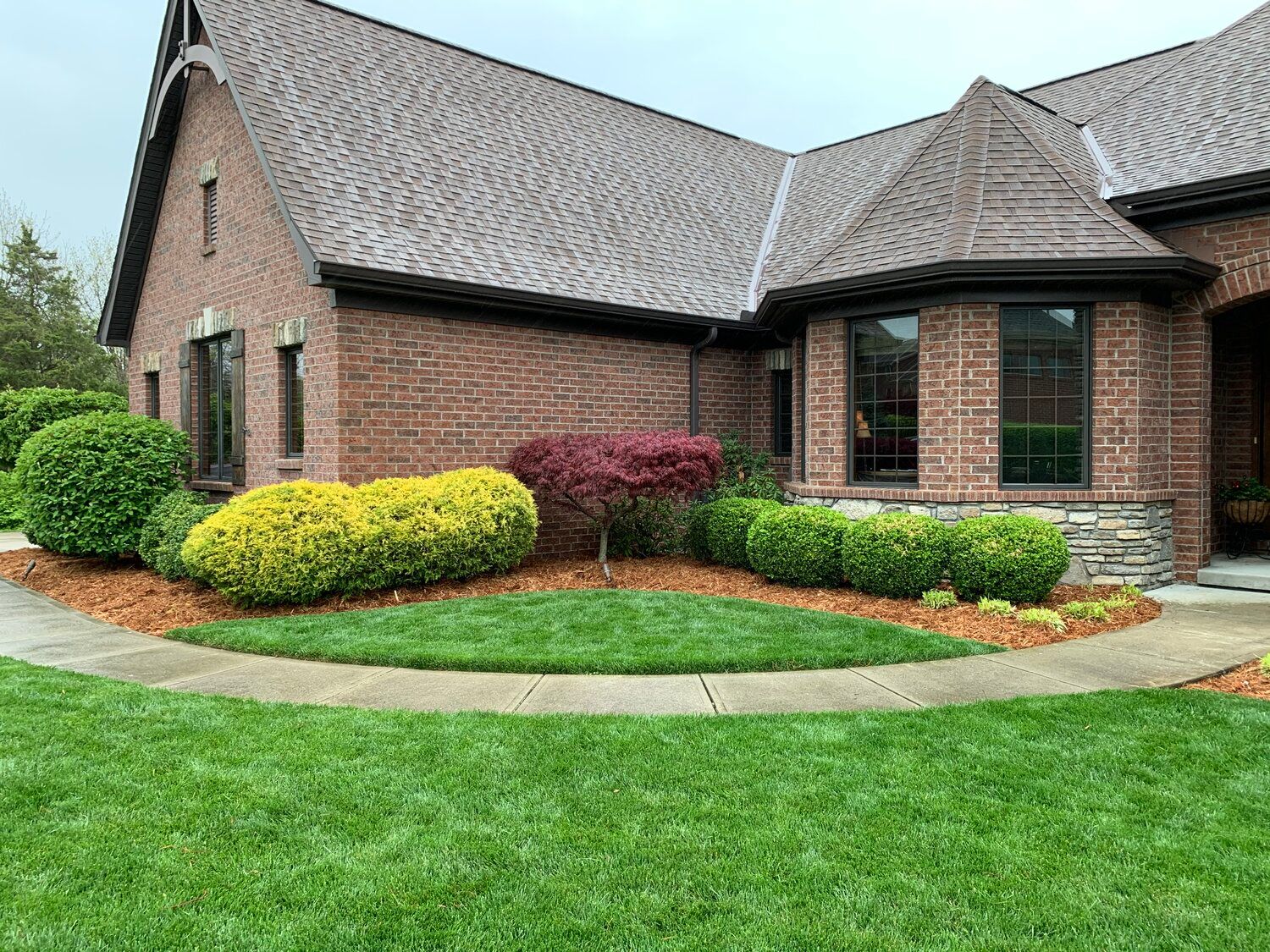 Brick house with a well-manicured lawn and colorful landscaping.