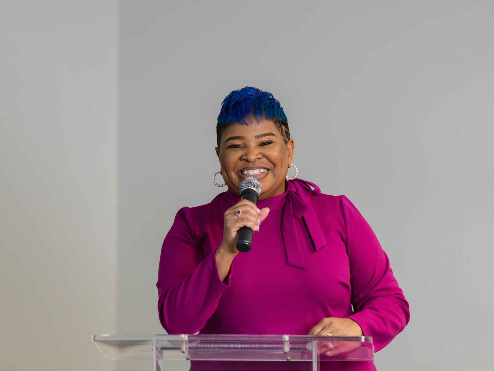 Daisy E. Brown speaking at a clear podium with a microphone in hand