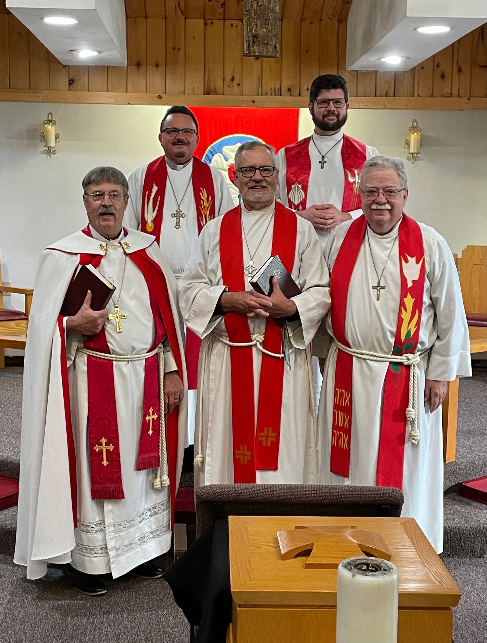 A group of priests are posing for a picture in a church.