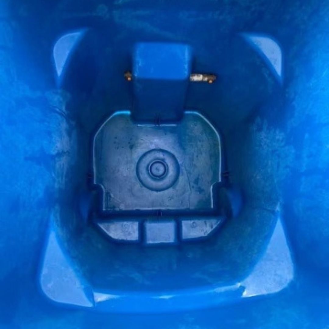 Blue trash bin interior with central blue plastic mechanism and small metal piece.
