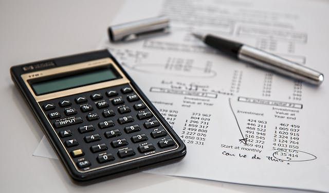 calculator and pen on top of financial documents
