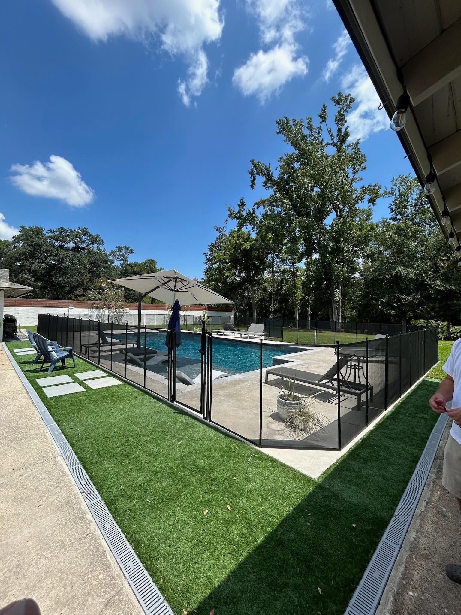 A backyard with a fence around a pool and a water table.