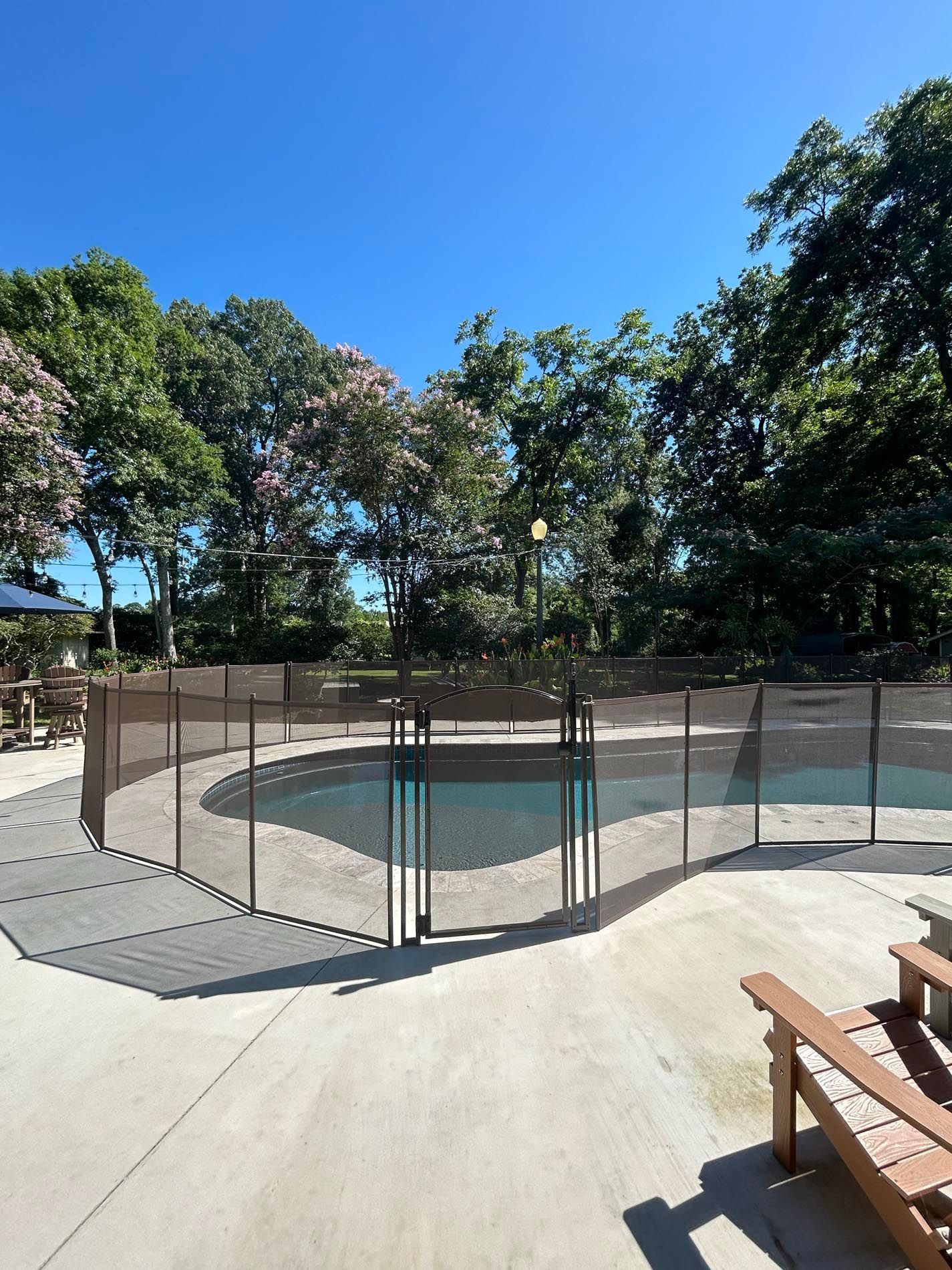 A swimming pool with a fence around it and trees in the background