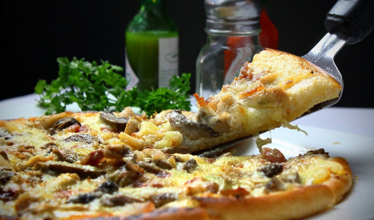 A slice of pizza is being taken out of a pizza with a spatula.