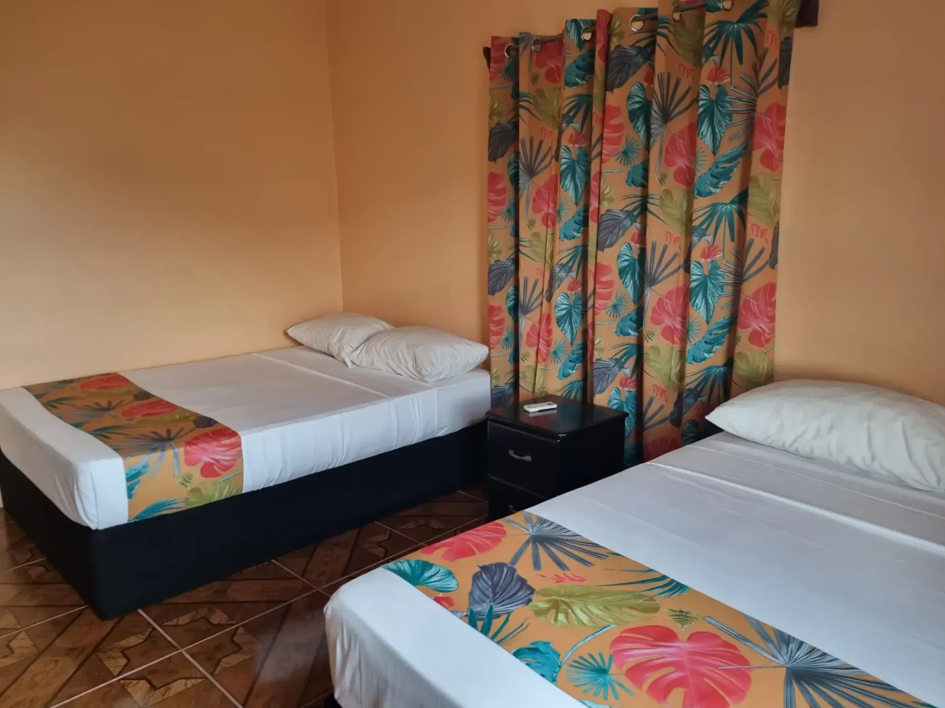 A hotel room with two beds and a nightstand.