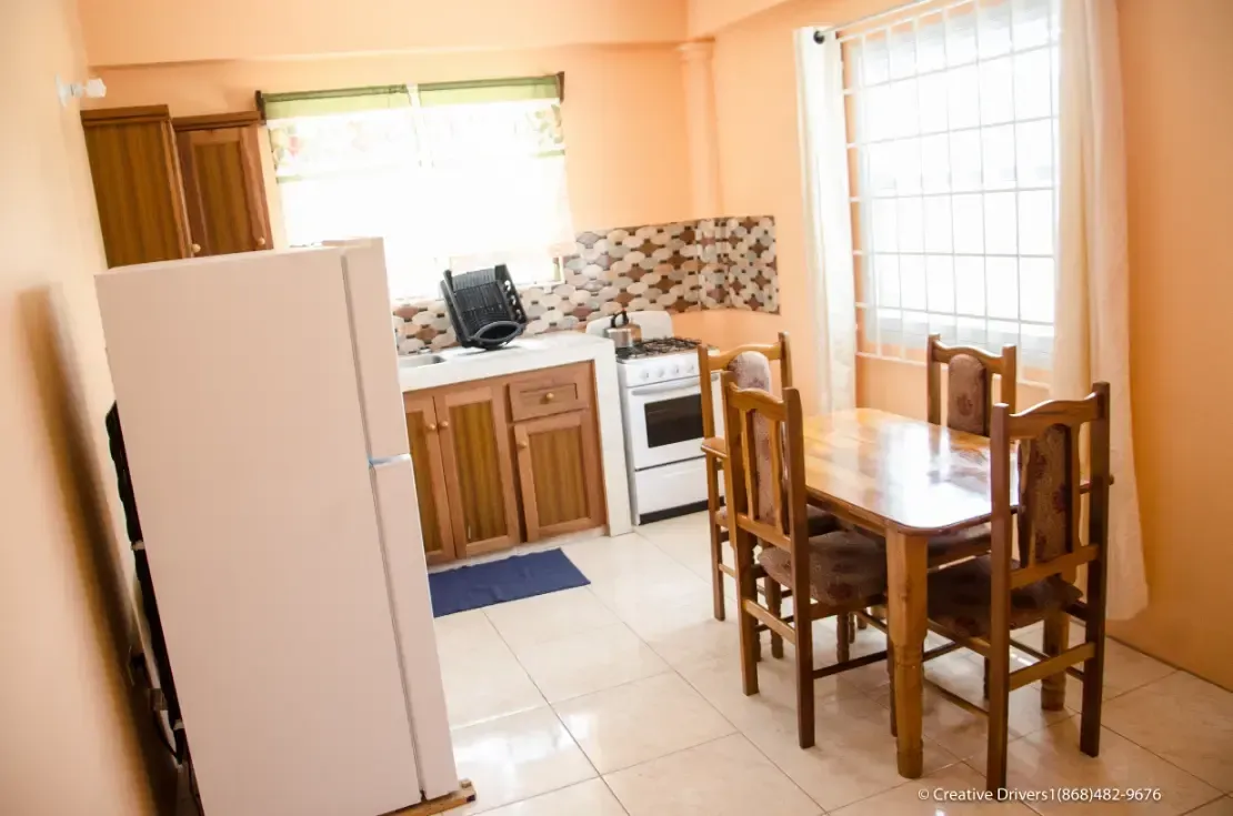 A kitchen with a table and chairs and a refrigerator.