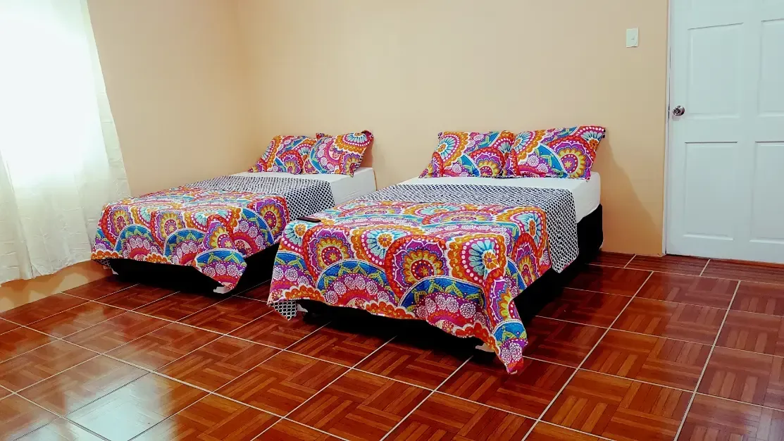A bedroom with two beds and a tiled floor.