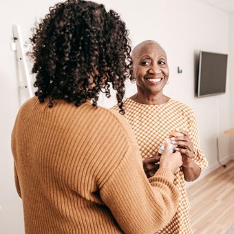NDIS Core Supports - 2 women smile and look at each other. One is a carer, the other lives with disability.