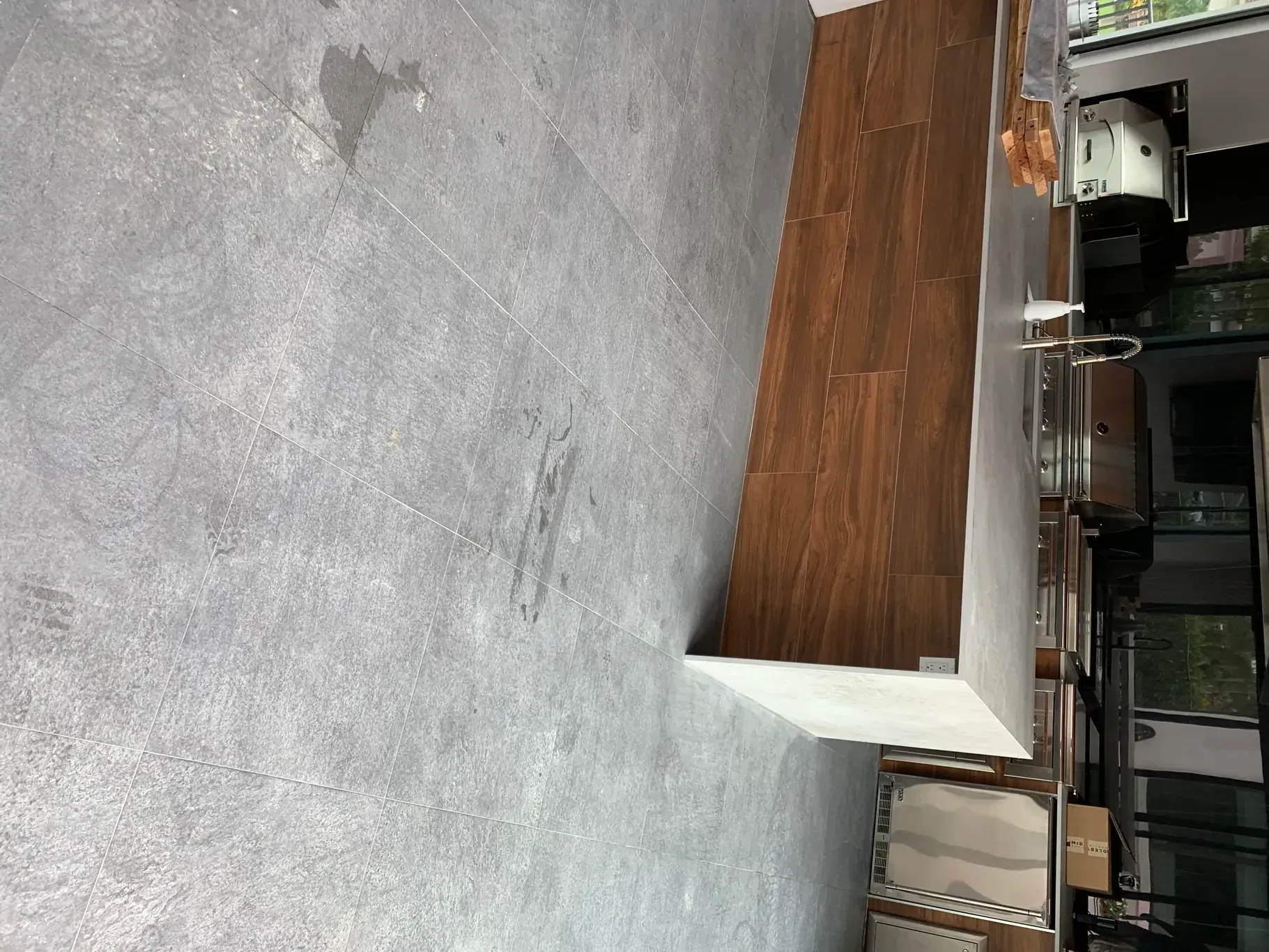 Empty indoor space with a gray carpeted floor and a small wooden counter or bench.