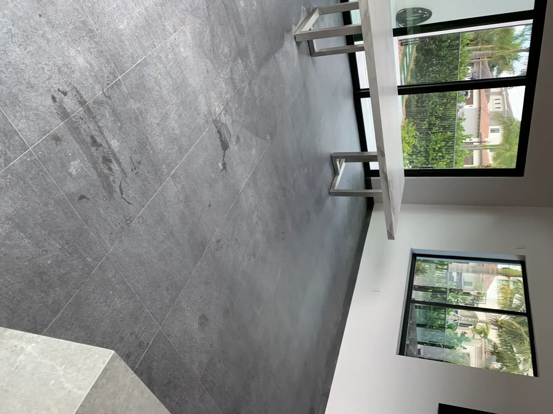 Empty modern room with concrete floor, large windows, and a long table near the wall.