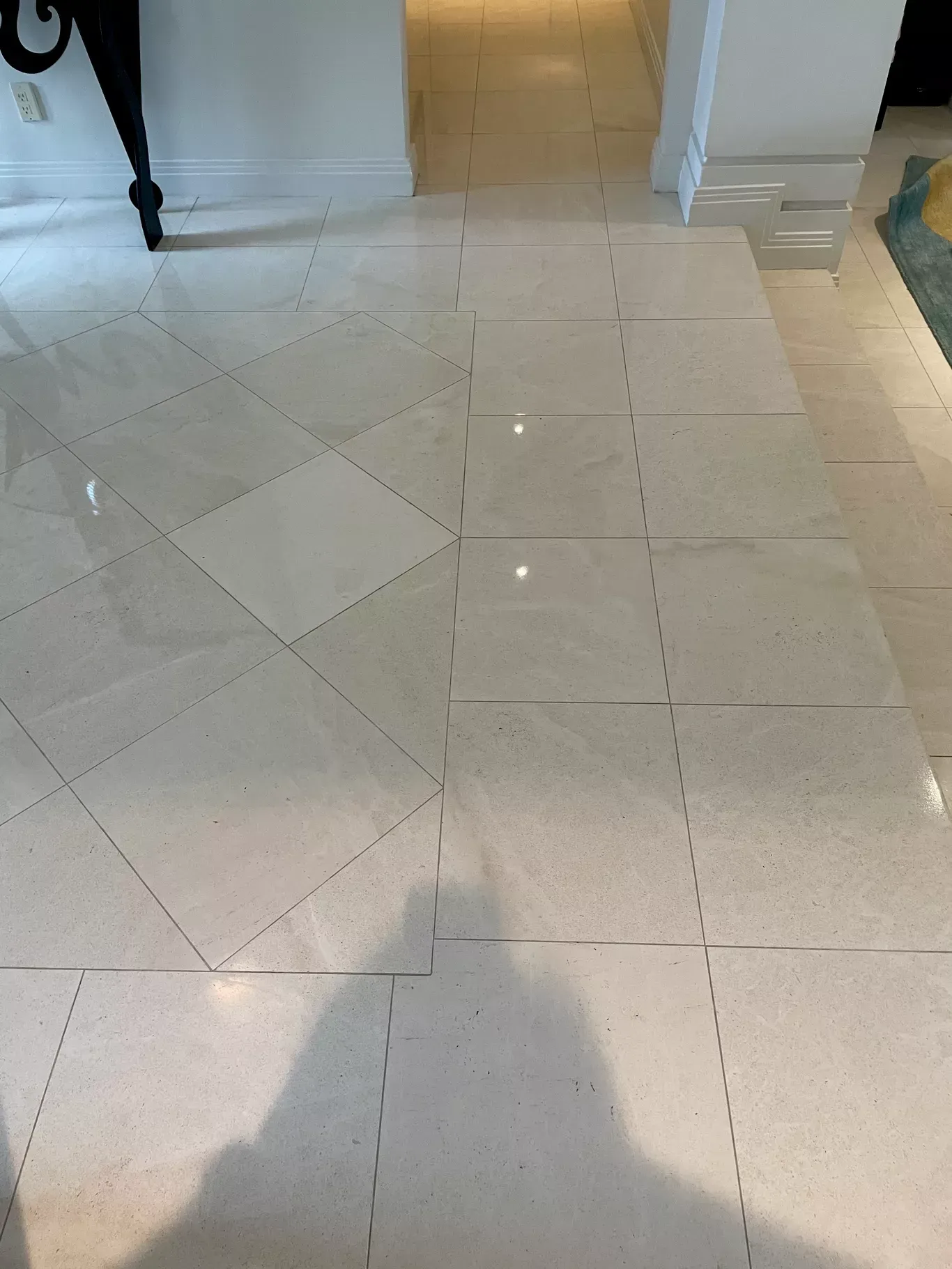 Glossy white tiled floor with diagonal and straight grout lines in a bright indoor hallway