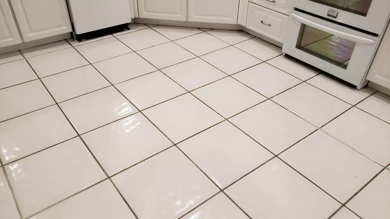 White tiled kitchen floor with white cabinets and built-in oven.