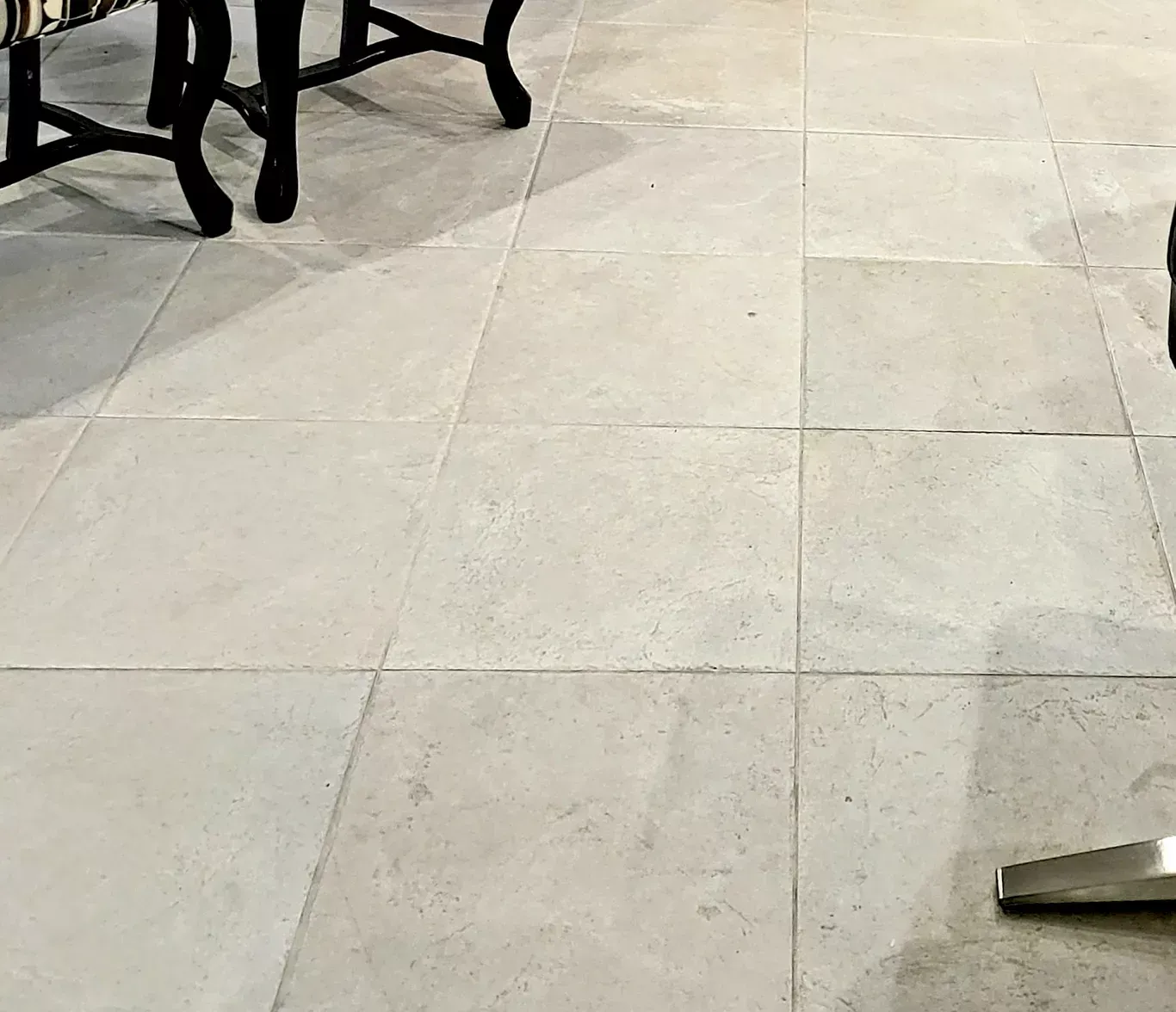Light beige tiled floor with table and chair legs visible at the edges, and a metal chair leg in the lower right.