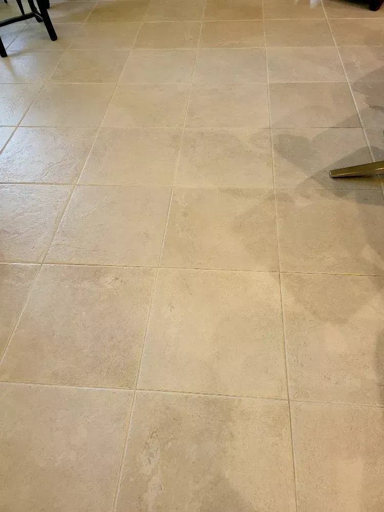 Beige tiled floor in a room, with chair legs visible at the edges.
