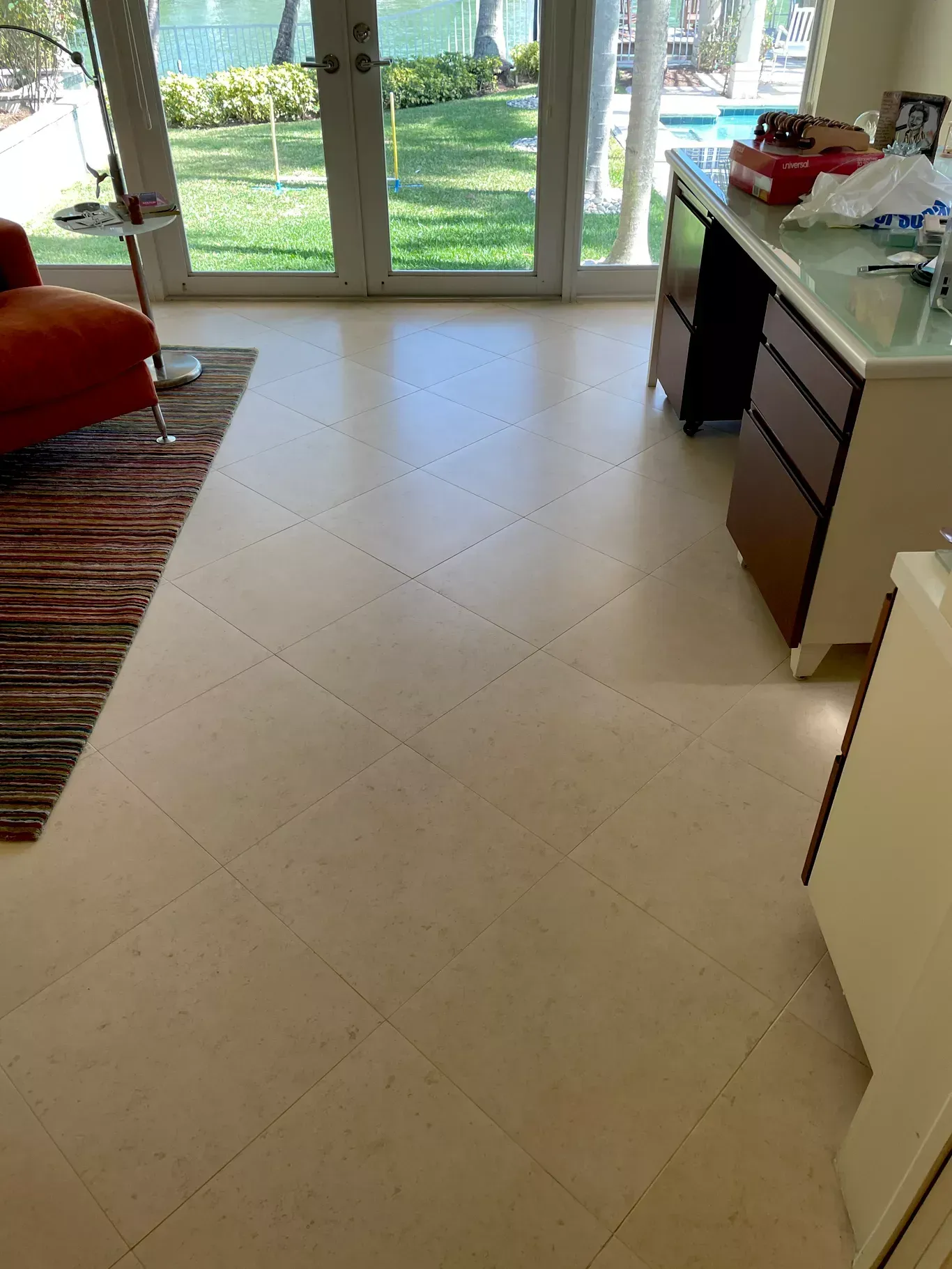 Bright kitchen with tiled floor, glass doors to a green yard, and a countertop with items on the right.