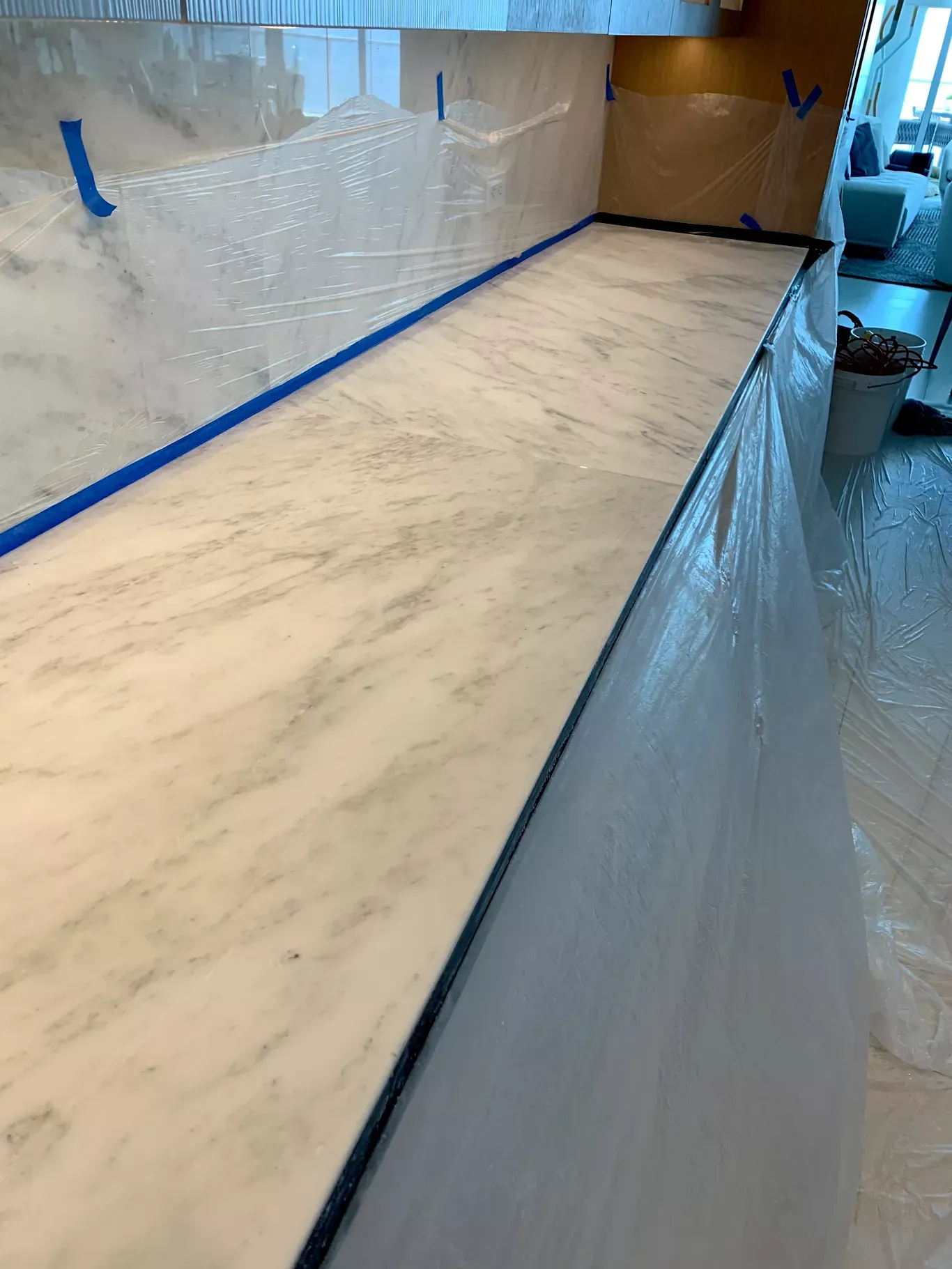 Marble countertop under clear protective plastic in a kitchen or workspace