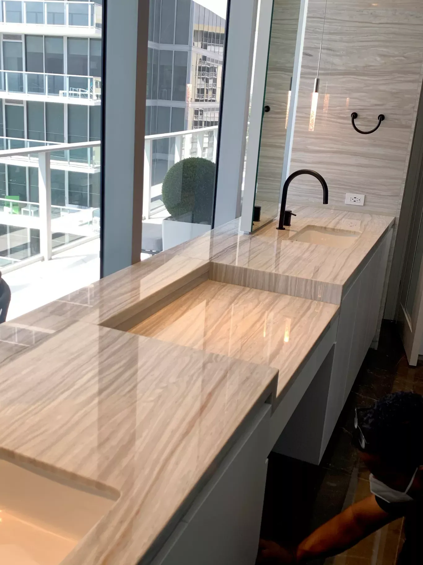Modern office kitchenette with light wood counters, black faucets, and floor-to-ceiling windows.
