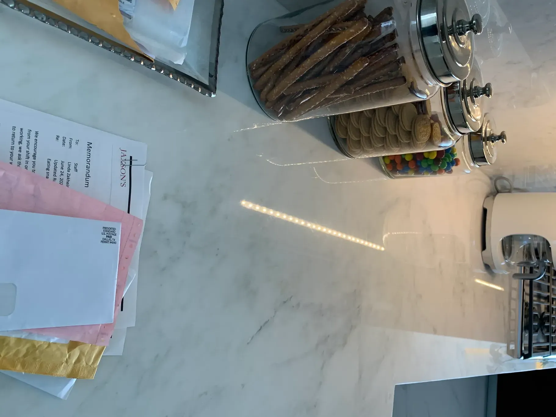 Countertop with glass jars of snacks and a notepad on a marble surface