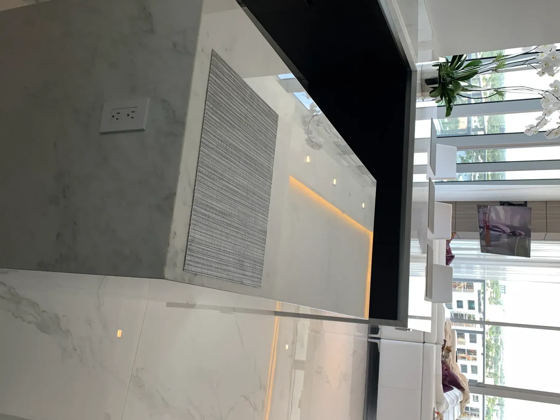 Modern lobby with marble walls, a reception desk, and large windows overlooking greenery.