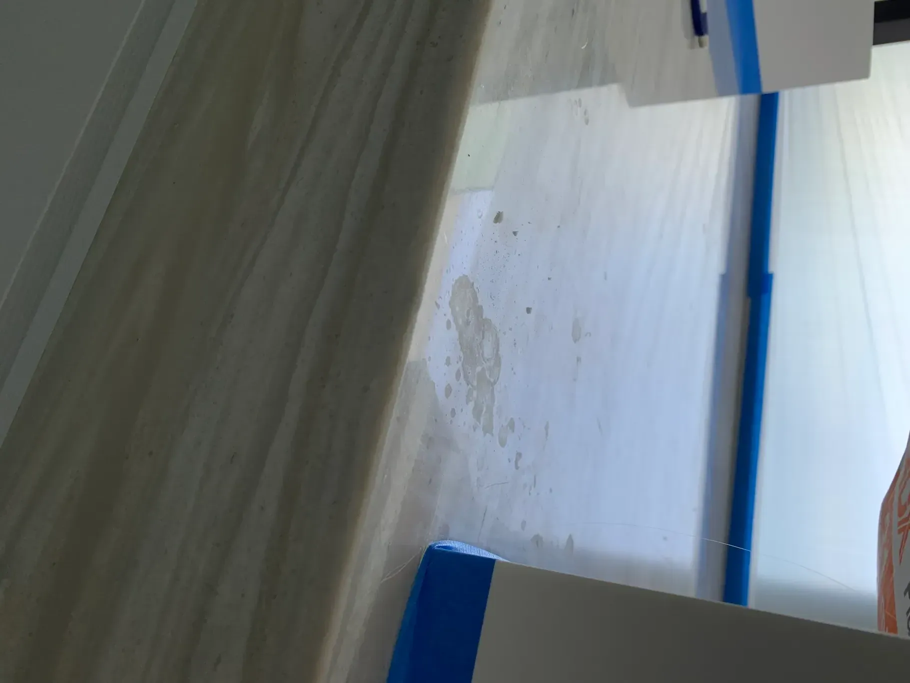 Close-up of a blue-and-white wall corner with a rough patch and a dark vertical beam