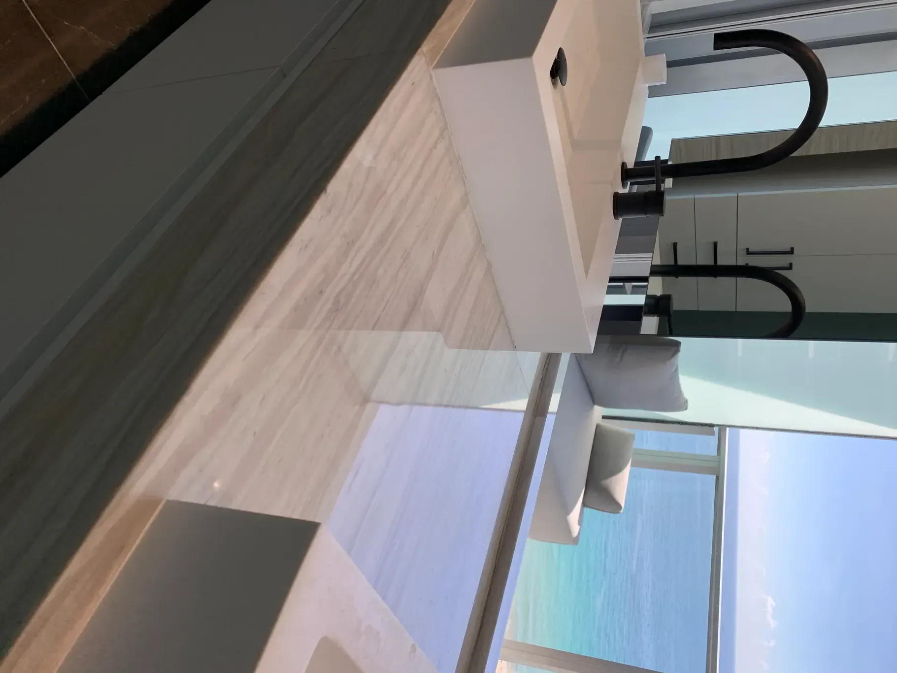 Modern kitchen with white cabinets, wood countertops, and a blue chair by a window.