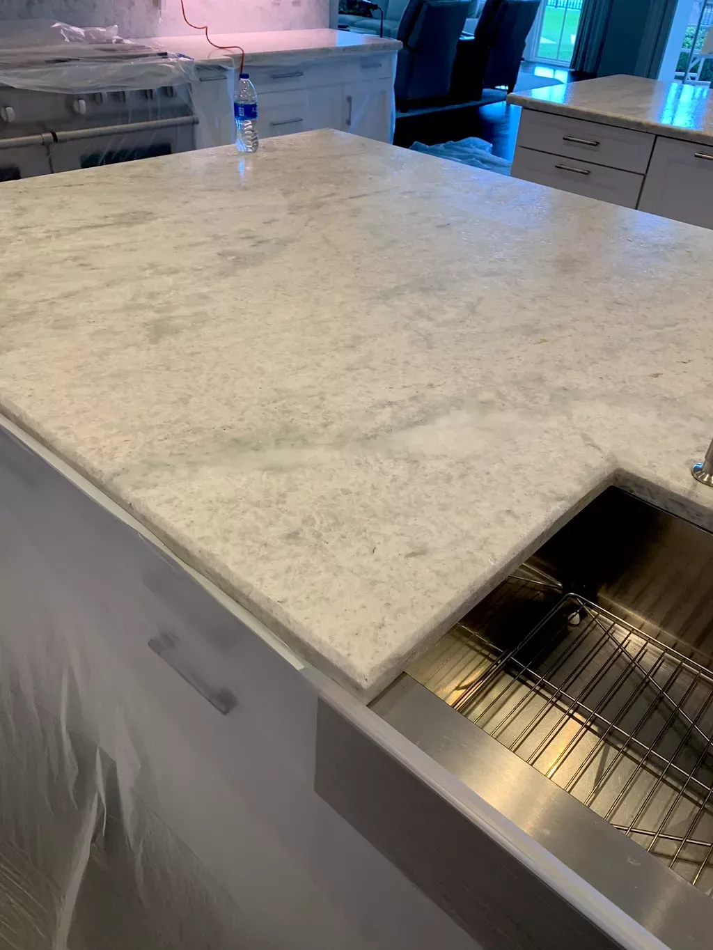 Kitchen island with white countertop and a built-in stainless-steel sink.