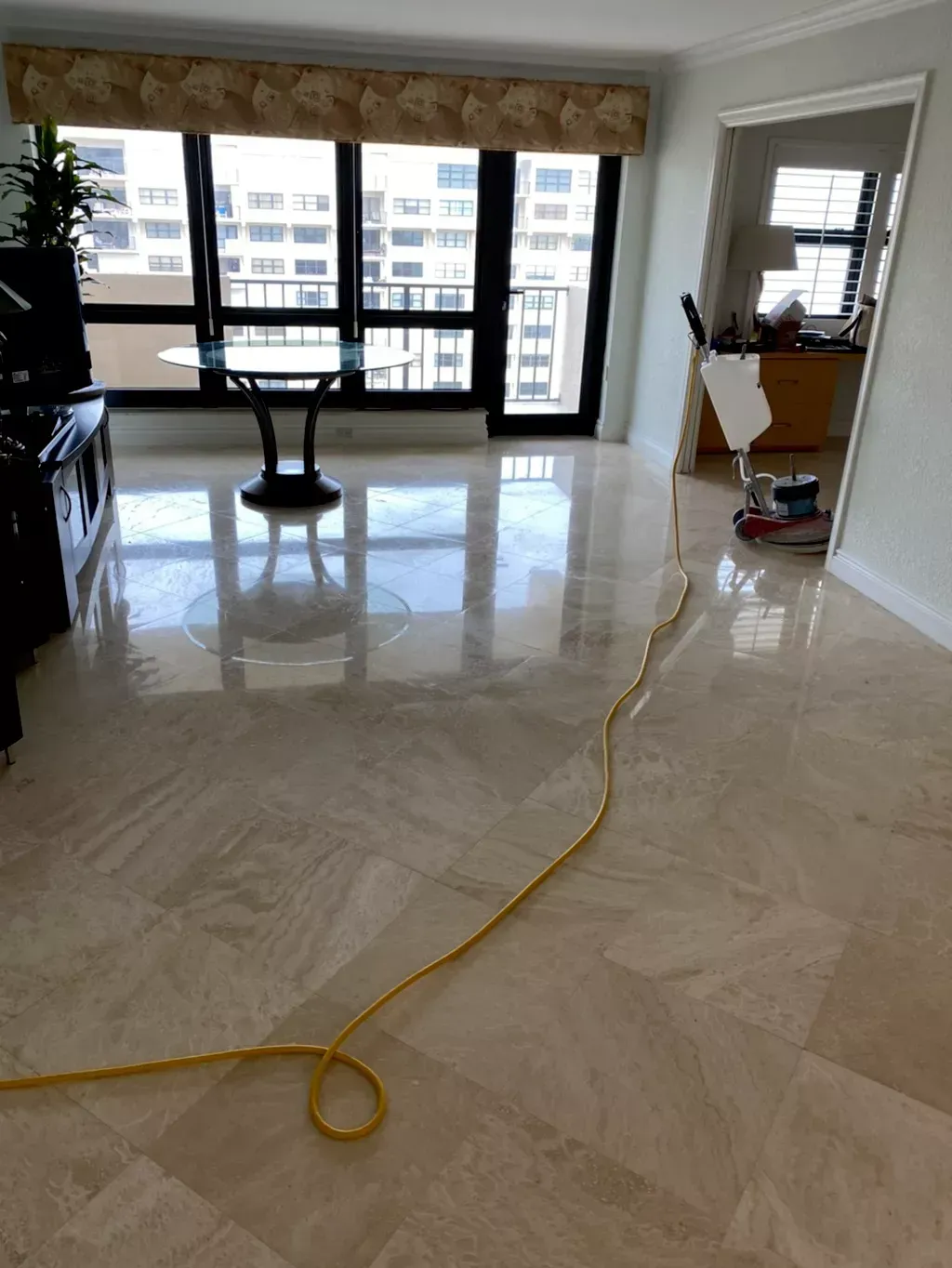 Bright living room with glossy tile floor, large windows, and a yellow cord across the floor