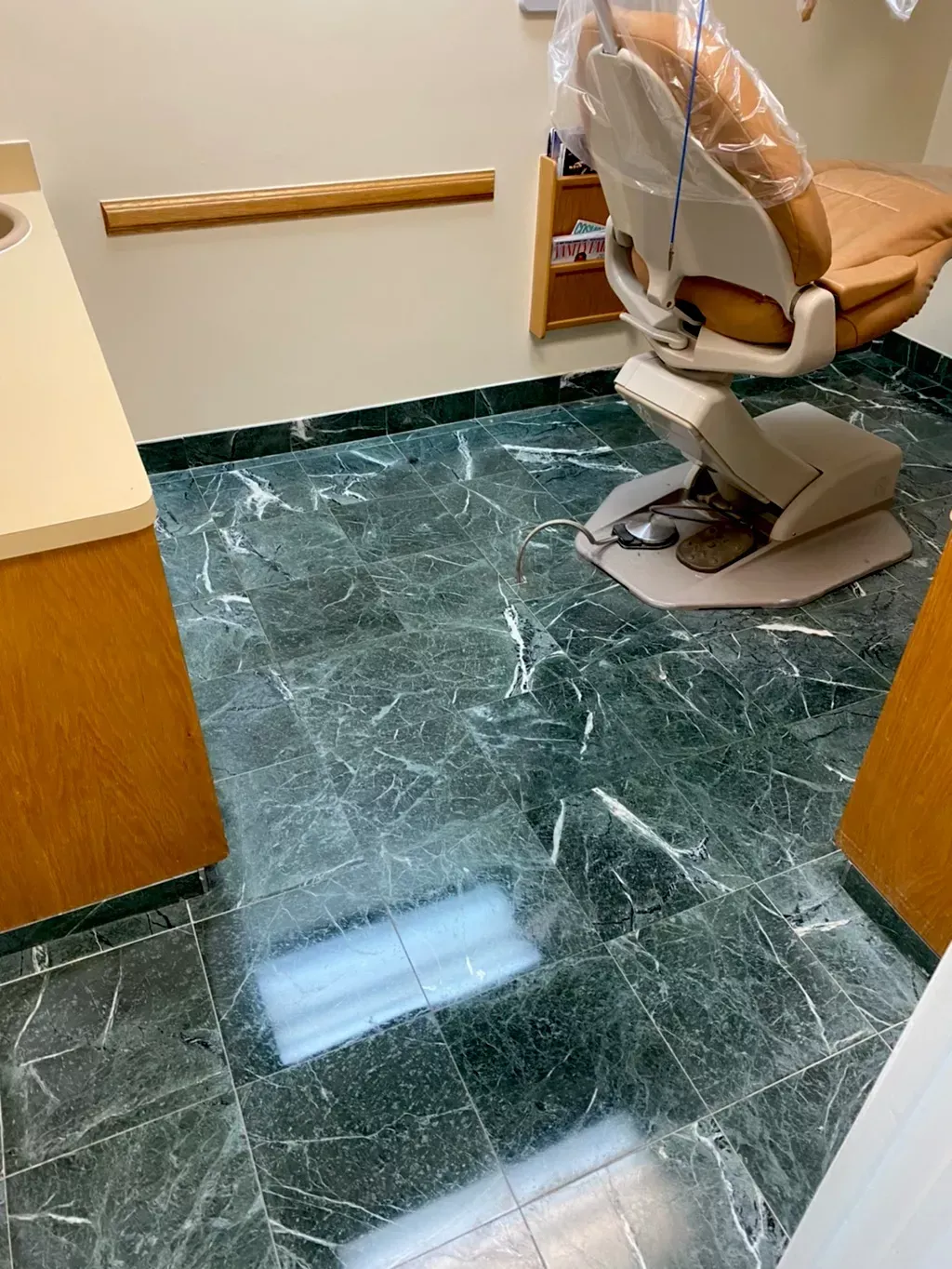 Dental exam room with green marble floor, chair, and wooden handrails visible