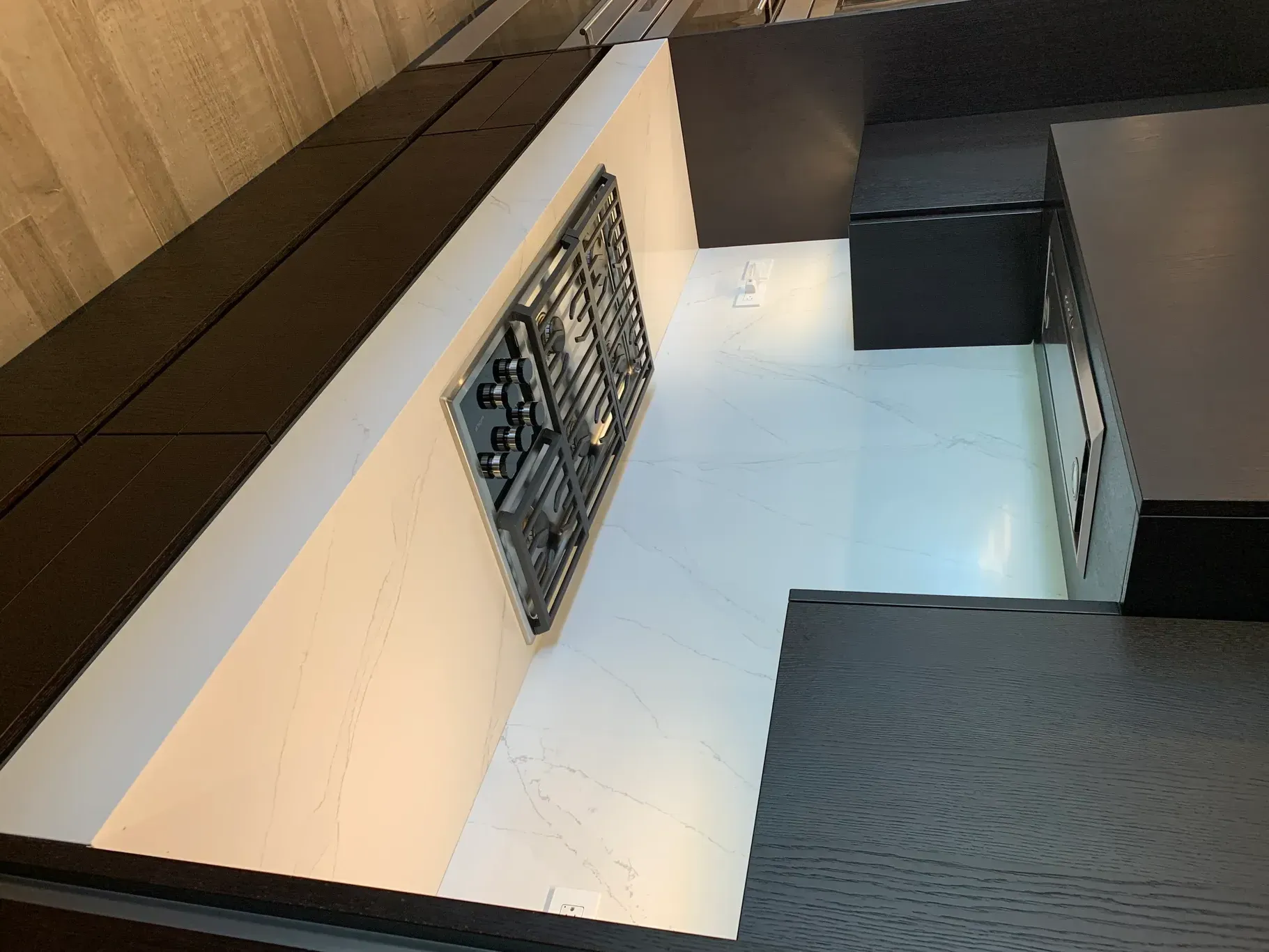 Modern kitchen with light cabinets, dark countertops, and a decorative wall panel near a stair landing
