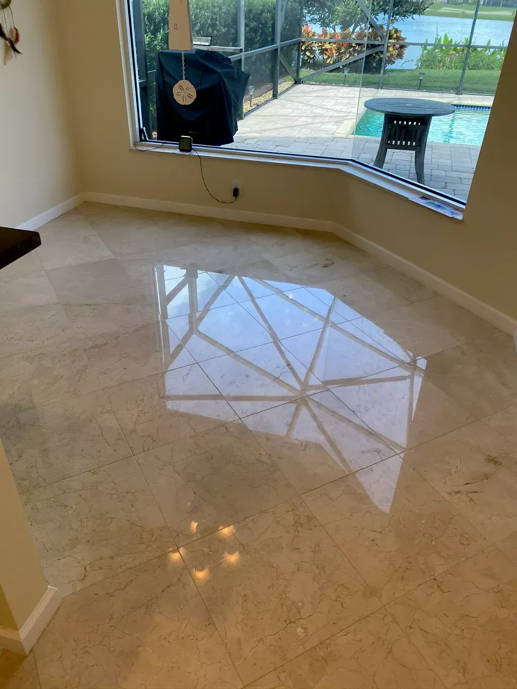 Empty glossy tiled room with a bay window, reflecting the patio and outdoors.