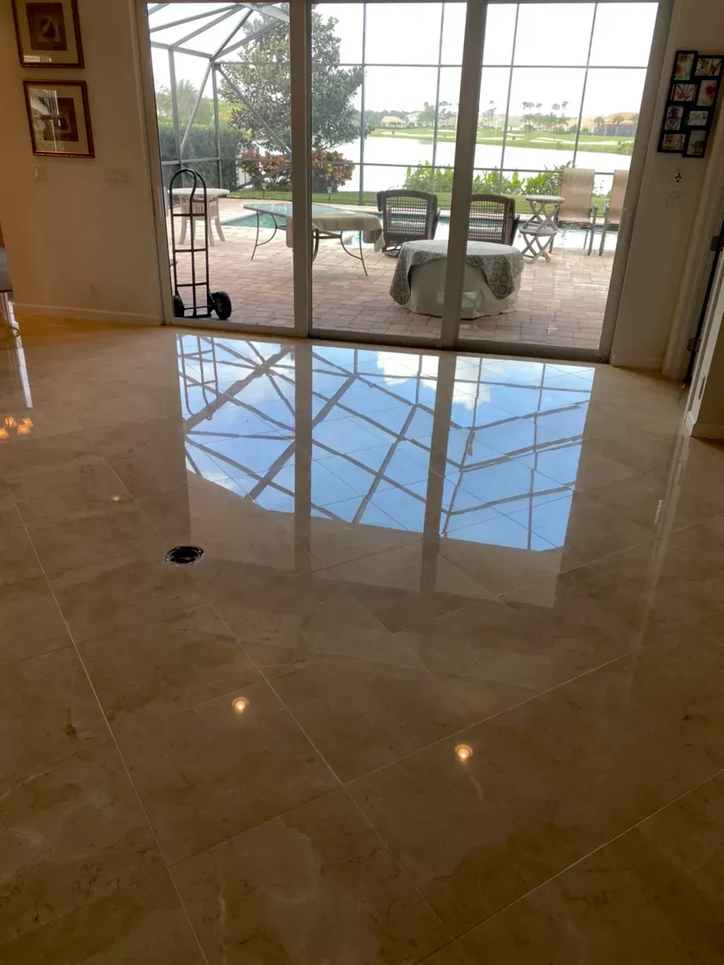 Polished tile floor reflecting glass doors opening to a patio with chairs and a lake view