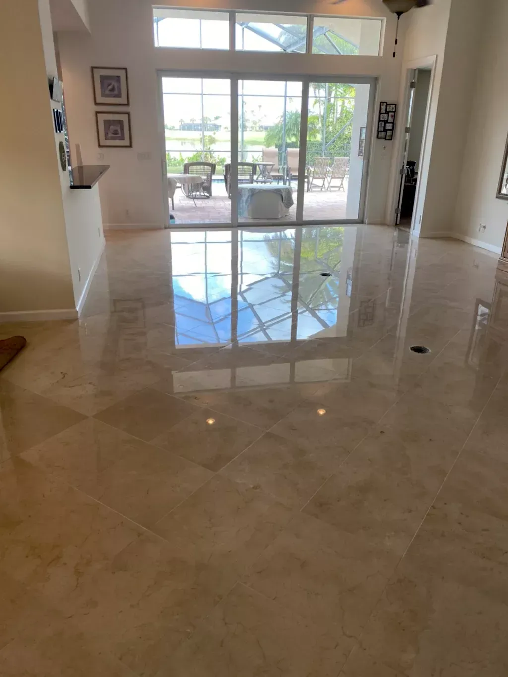 Bright marble-floored living room with large windows and sliding glass doors opening to a patio.