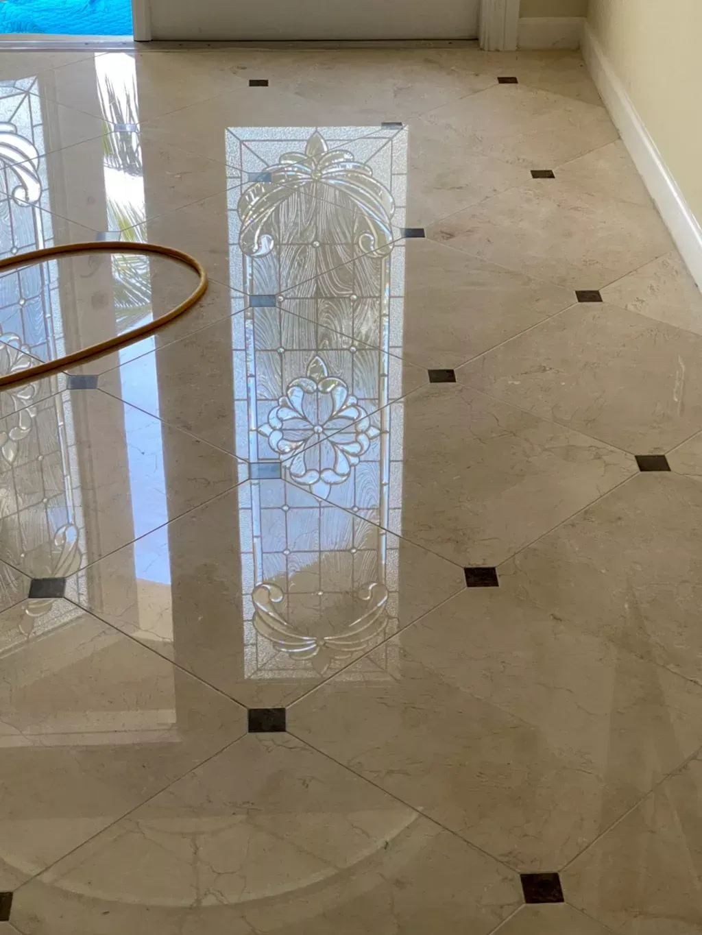 Glossy tiled floor with small dark inlays and a decorative frosted glass reflection near a doorway