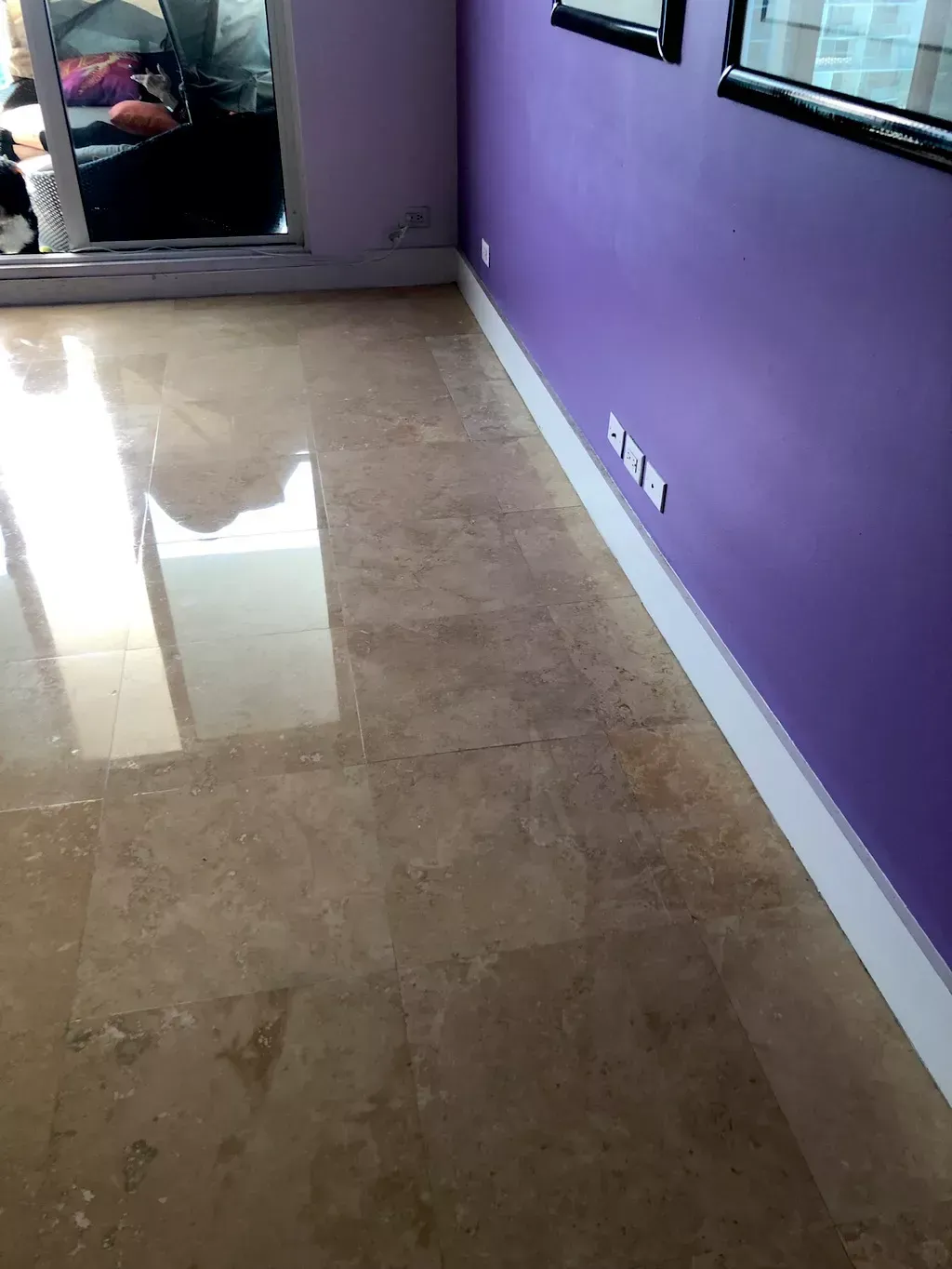 Purple-walled room with polished beige tile floor and a sliding glass door reflecting light.