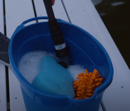 Blue bucket with boat cleaning supplies, such as a sponge, soap, towel.