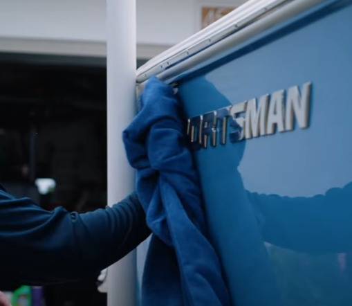 Man wiping silver Sportsman logo clean with chamois towel.