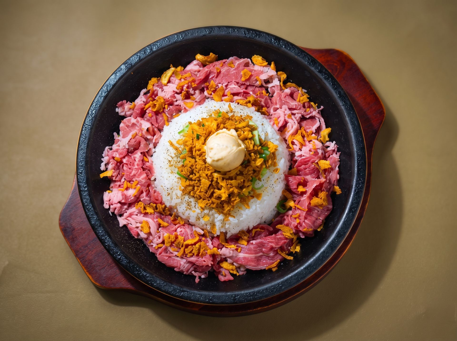 Bowl of rice topped with pink shredded meat and a dollop of butter on a tan table.