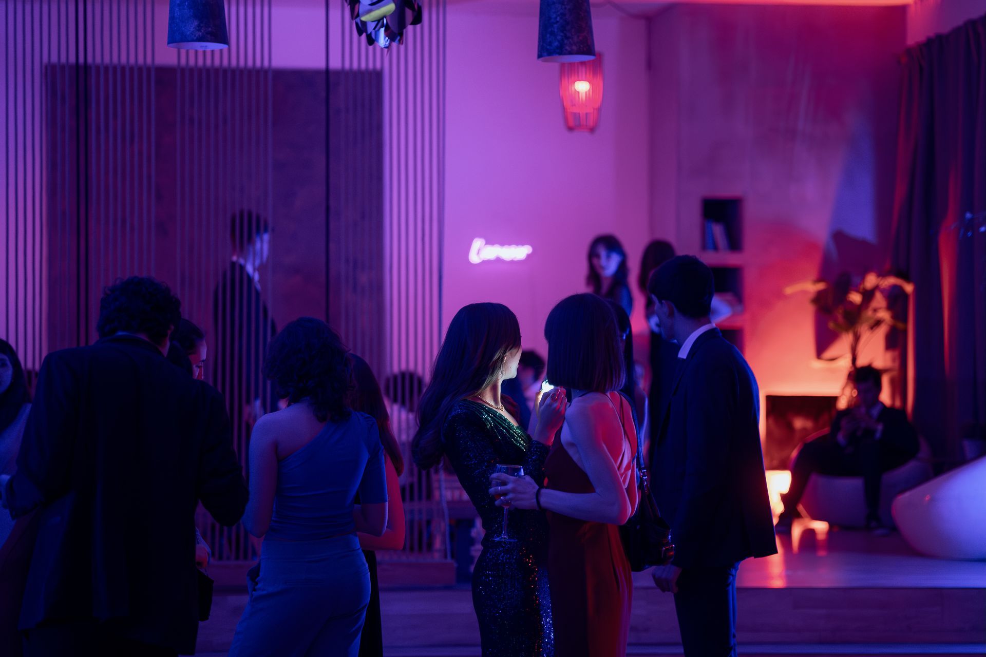Due persone in abito elegante ballano in uno spazio per eventi affollato e scarsamente illuminato.